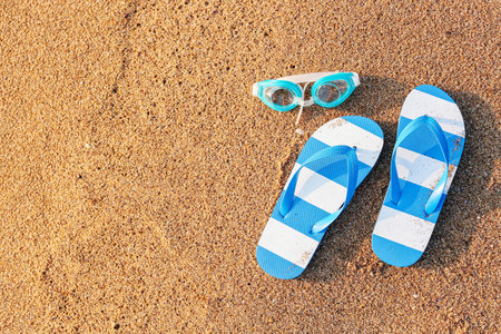 Stylish flips flops with goggles on sand at resortの写真素材