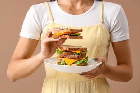 Young woman with big sandwich on color background, closeupの写真素材