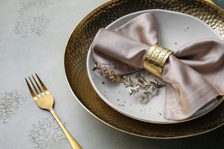 Elegant table setting with golden leaves and fork on gray table, closeup
