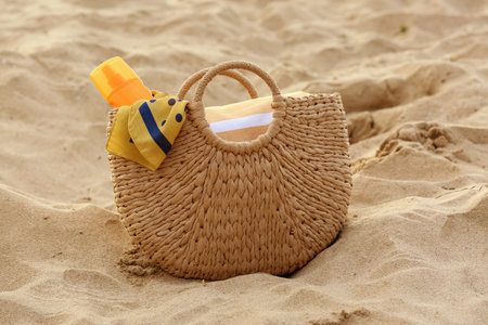 Wicker bag with different beach accessories on sand at resortの写真素材