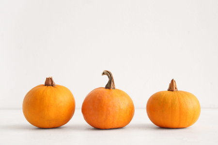 Raw pumpkins for Halloween celebration on light background