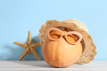 Halloween pumpkin with beach accessories and starfish on light wooden tableの写真素材