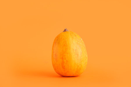 Raw pumpkin for Halloween celebration on orange backgroundの写真素材