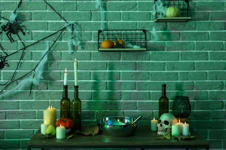 Burning candles with pumpkins and Halloween decor on table in dark roomの写真素材