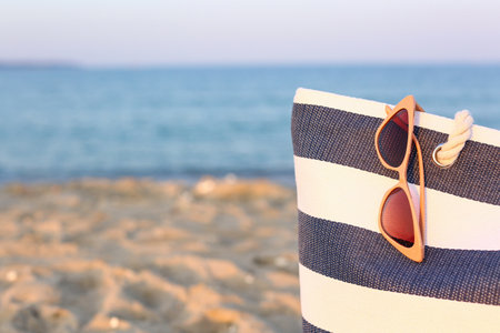 Stylish sunglasses and bag on seashoreの写真素材
