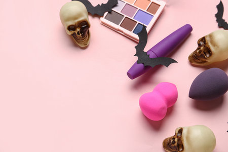 Different decorative cosmetics with paper bats and human skulls for Halloween on pink backgroundの写真素材