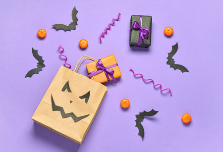 Composition with shopping bag, gifts and Halloween decorations on lilac backgroundの写真素材