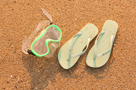 Stylish flips flops with snorkeling mask on sand at resortの写真素材