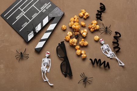 Movie clapperboard, caramel popcorn and Halloween decor on brown grunge backgroundの写真素材