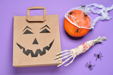 Shopping bag and Halloween decorations on lilac backgroundの写真素材