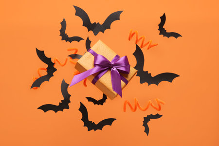 Flying gift box and Halloween decoration on orange backgroundの写真素材