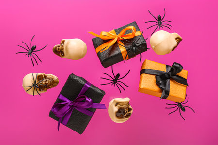 Flying gift boxes, spiders and skulls for Halloween celebration on pink backgroundの写真素材