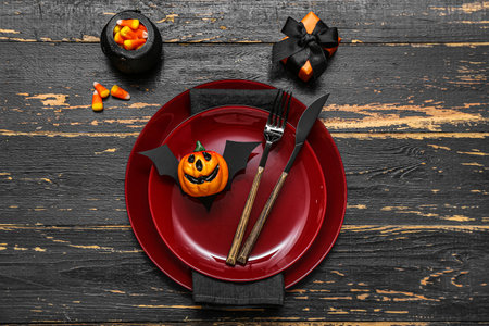 Festive table setting with Halloween bat and pumpkin on black wooden backgroundの写真素材