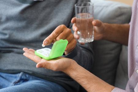 Senior man with his taking son pills at home, closeupの写真素材