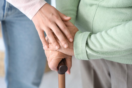 Senior woman with walking stick and her daughter at home, closeupの写真素材