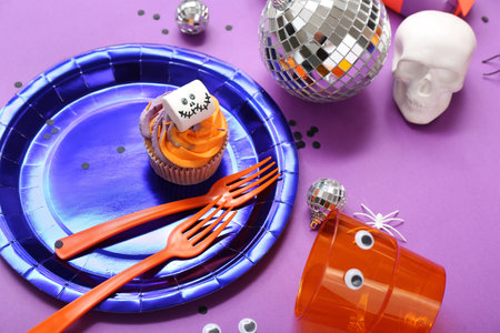Halloween party table setting with cupcake, disco ball and skull on purple backgroundの写真素材