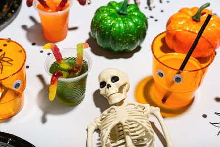 Halloween party table setting with punch, skeleton and gummy worms on white backgroundの写真素材