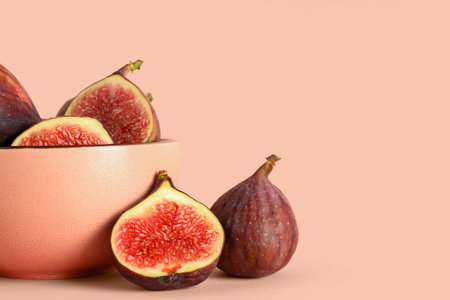 Bowl with fresh juicy cut figs on pale pink background
