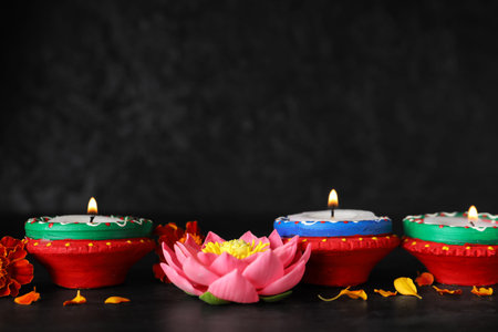 Candles with lotus and marigold flowers on grunge black background. Divaly celebration