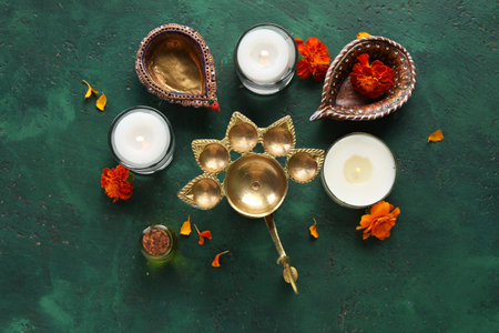 Diya lamps with candles, aroma oil and marigold flowers on grunge green background. Divaly celebrationの写真素材