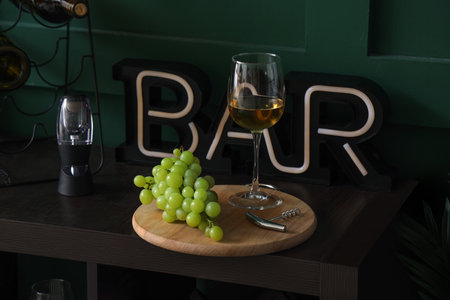 Board with glass of tasty wine and grapes on table, closeupの写真素材