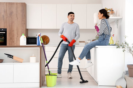 Happy young couple cleaning in kitchenの写真素材