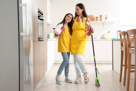 Happy mother with her little daughter hugging while cleaning in kitchenの写真素材