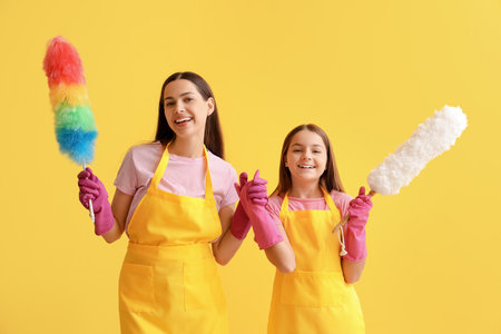 Happy mother with her little daughter and pp-dusters on yellow backgroundの写真素材