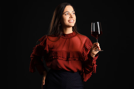 Young woman with glass of wine on black backgroundの写真素材