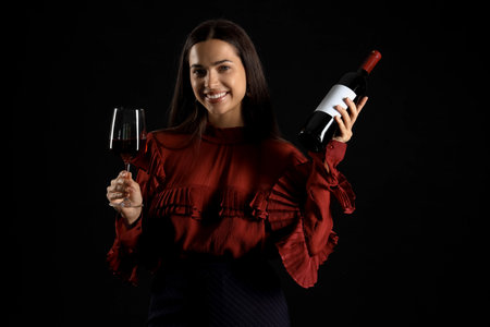 Young woman with glass and bottle of wine on black backgroundの写真素材