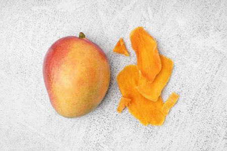 Slices of dried mango and fresh fruit on white backgroundの写真素材