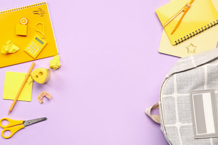 Stylish school backpack with different stationery supplies on lilac backgroundの写真素材
