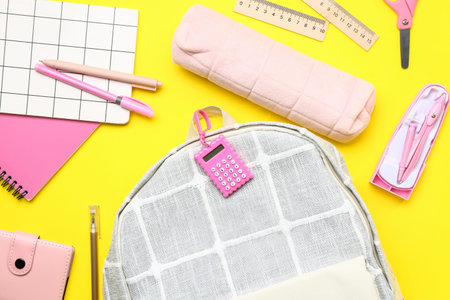 Stylish school backpack with different stationery supplies on yellow background