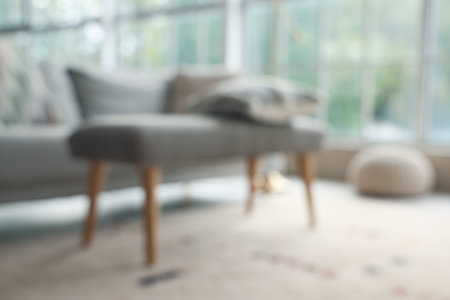Blurred view of soft bench with pillow in living room