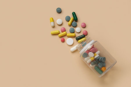 Jar with different scattered pills on beige backgroundの写真素材