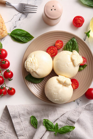 Plate of tasty Burrata cheese with basil and tomatoes on white background