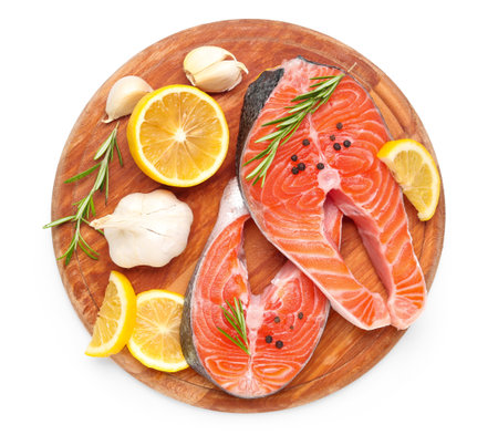 Wooden board with raw salmon steaks and different spices on white backgroundの写真素材