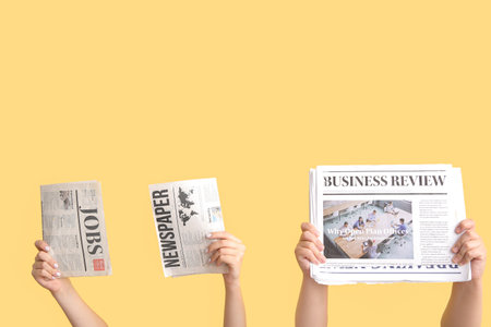 Female hands with different newspapers against color backgroundの写真素材