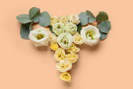 Uterus made of paper and beautiful flowers on beige background
