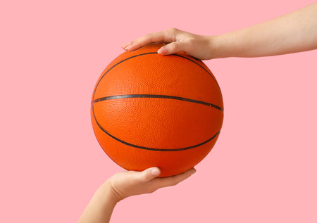 Female hand holding ball for playing basketball on pink backgroundの写真素材