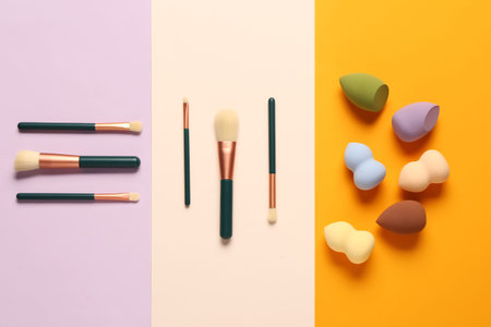 Makeup sponges and brushes on colorful background