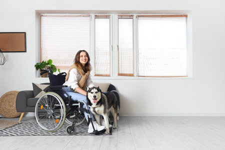 Young woman in wheelchair and with husky dog at homeの写真素材