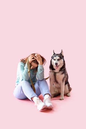 Depressed young woman with husky dog on pink backgroundの写真素材