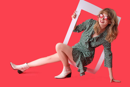 Young woman in sunglasses with frame on red backgroundの写真素材