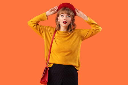 Stylish young woman in fall clothes on orange backgroundの写真素材