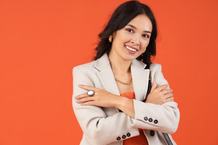 Stylish young Asian woman in fall clothes on red backgroundの写真素材