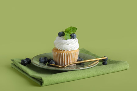 Plate of tasty cupcake with blueberries on green backgroundの写真素材