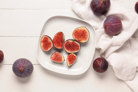 Plate with cut fresh figs on white wooden backgroundの写真素材