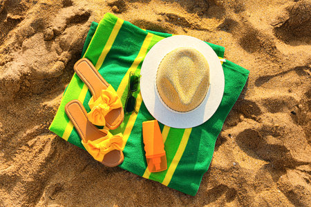 Stylish flips flops with beach accessories on sand at resort