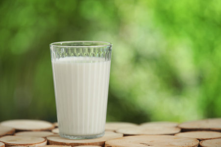 Glass of fresh milk on wooden table outdoorsの写真素材